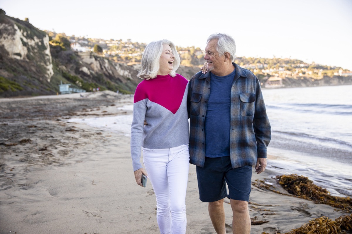 happy older couple walking on the beach