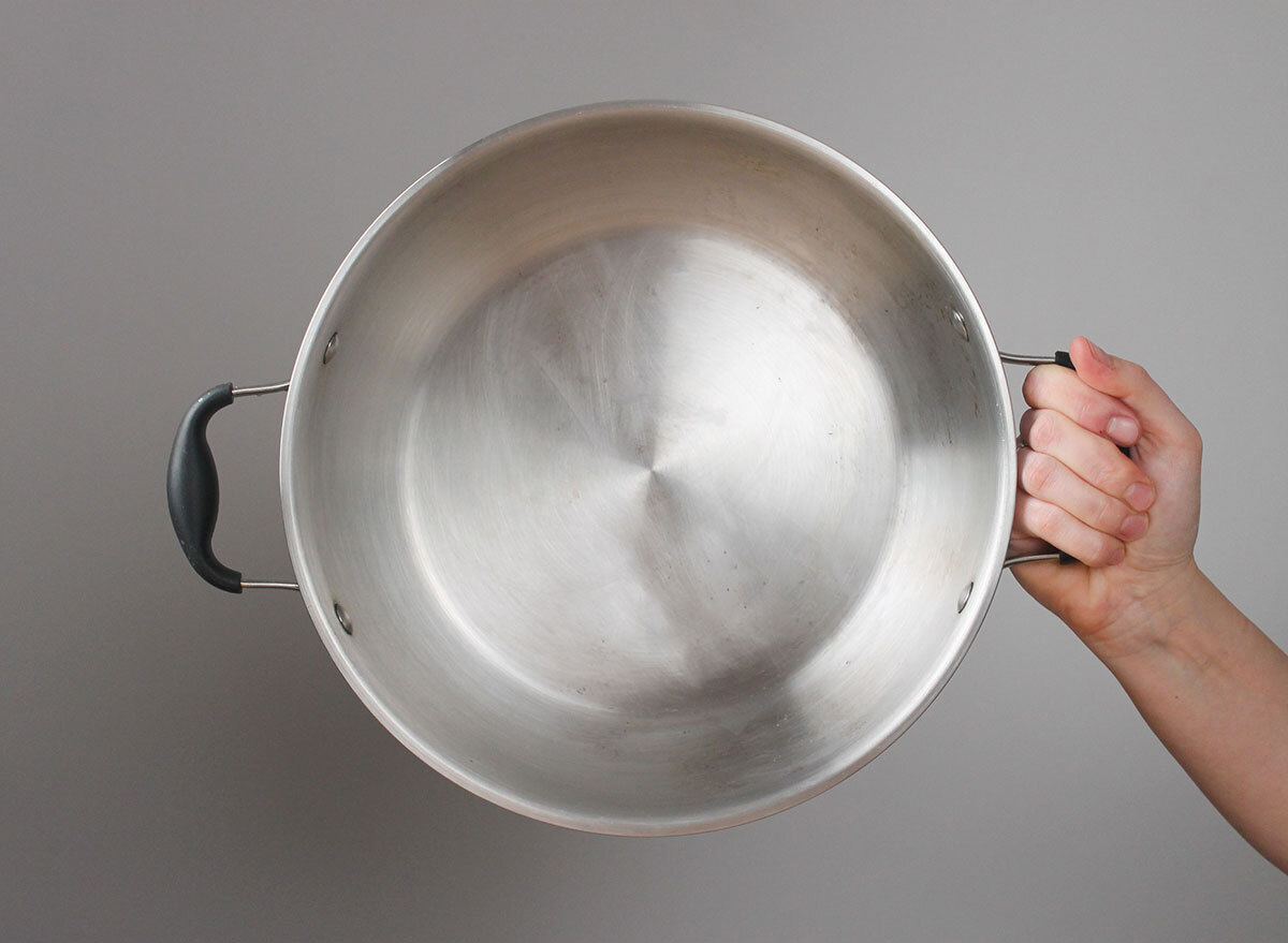 hand holding a clean pot against a grey background