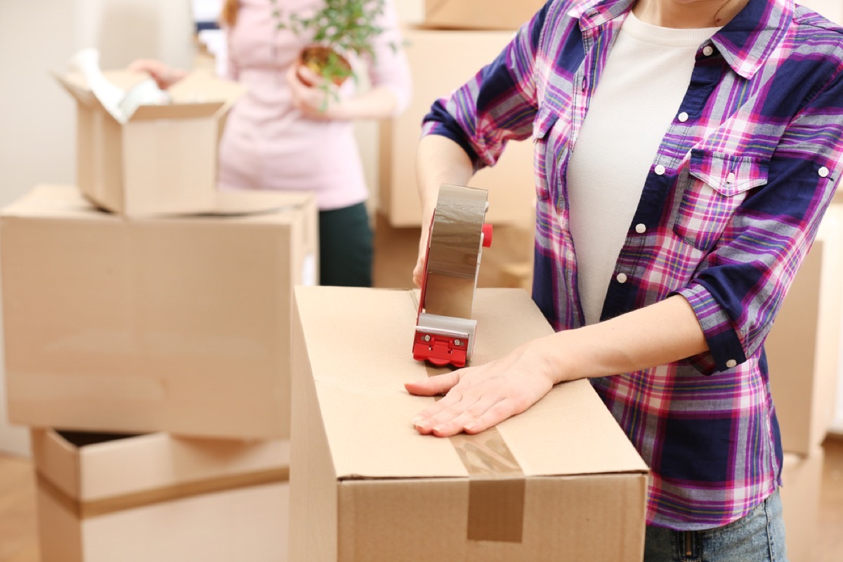 women taping moving boxes, downsizing your home