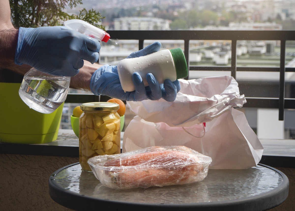 Man wiping down items and groceries with disinfectant or sanitizer spray