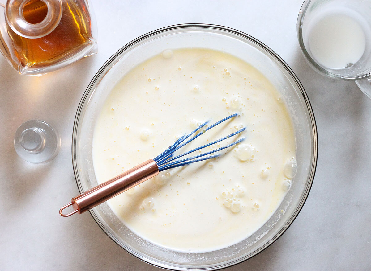 whisking egg mixture for eggnog with milk mixture and alcohol