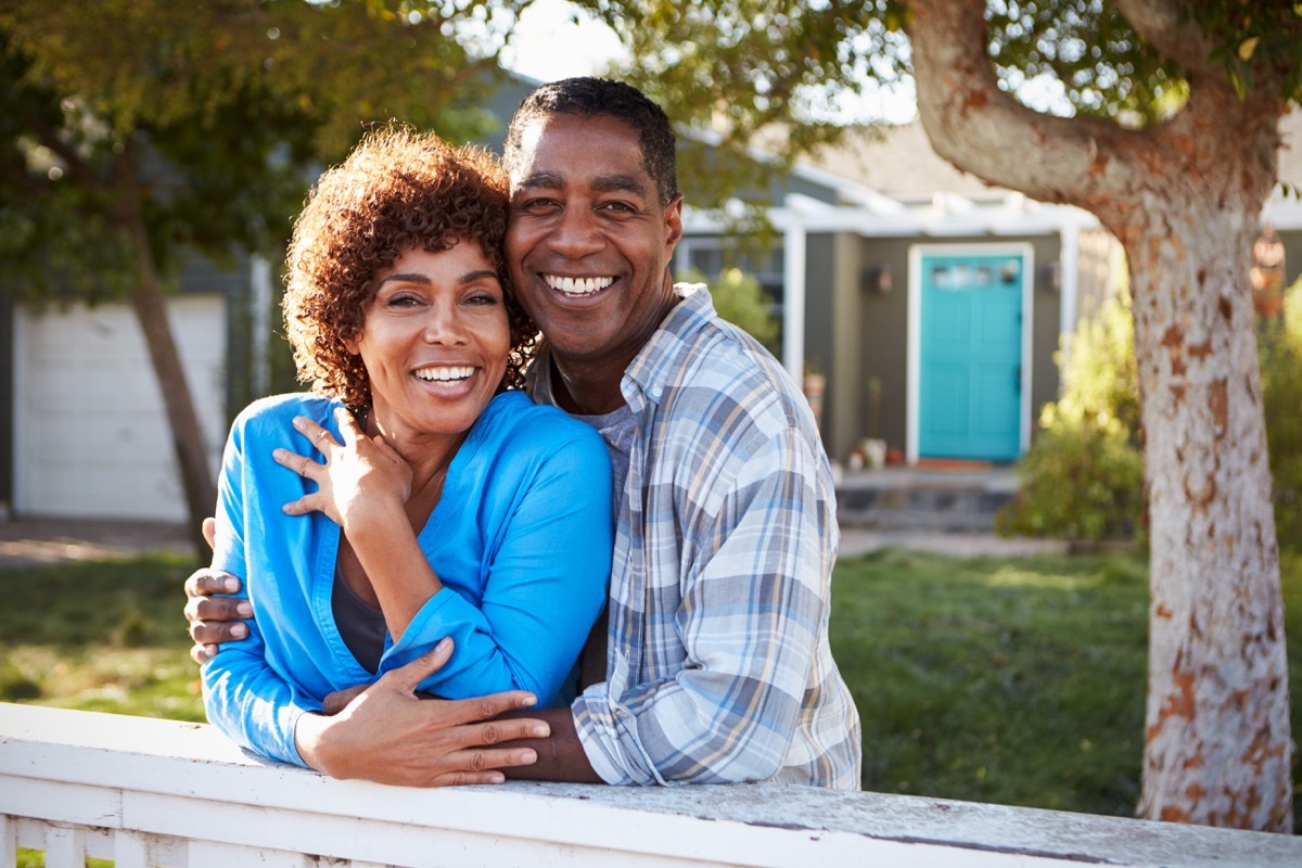 Black couple smiling in embrace on front lawn in sunshine