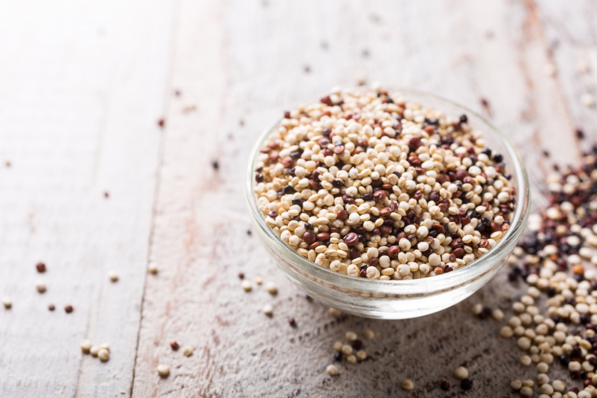 Pile of mixed raw quinoa, South American grain, in glass bowls on white rustic wooden background