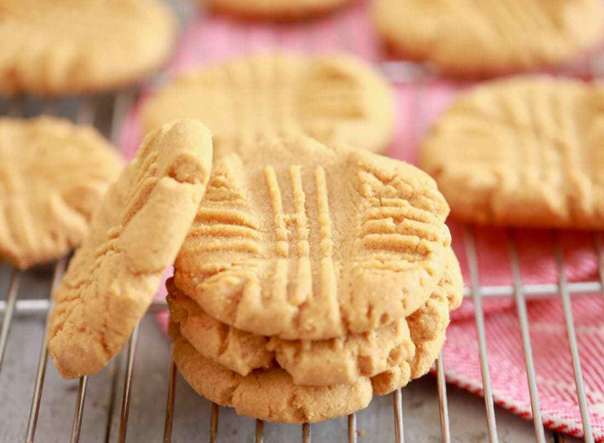 Peanut butter cookies stacked up on a cooling rack with a pink napkin