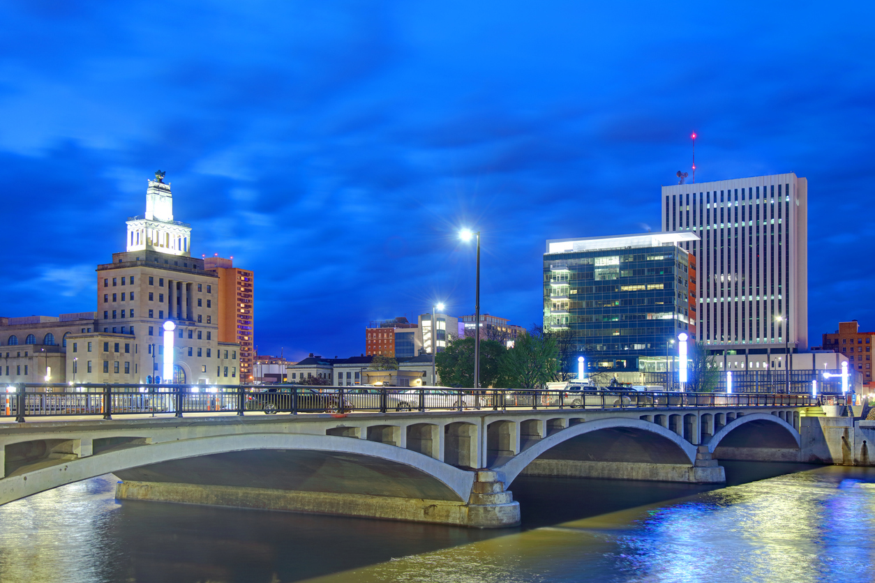 The skyline of Cedar Rapids, Iowa at night with a view of a bridge.