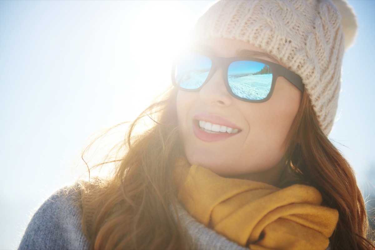 cheerful woman wearing shades enjoying sun in winter