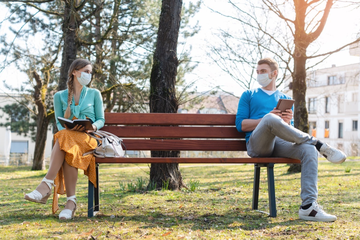 man and woman social distancing on bench