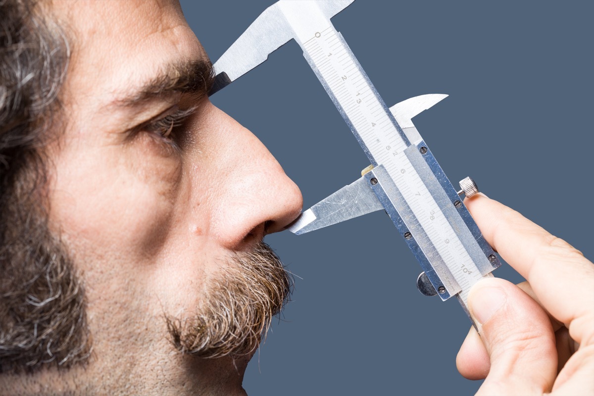 close up of man measuring his nose, big nose