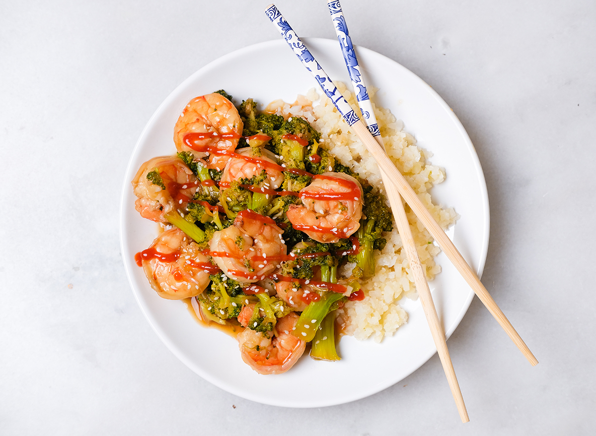 shrimp and broccoli with sriracha on a plate with cauliflower rice