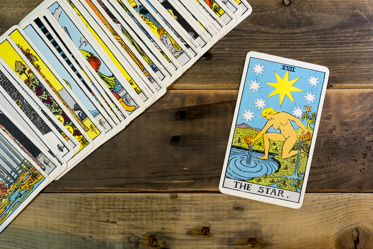 The Star tarot card with a laid out deck behind it