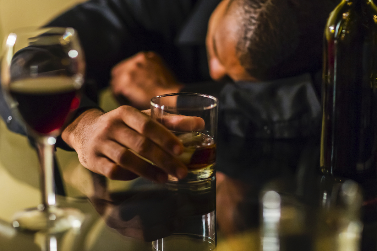 Drunk man with alcohol sleeping on table