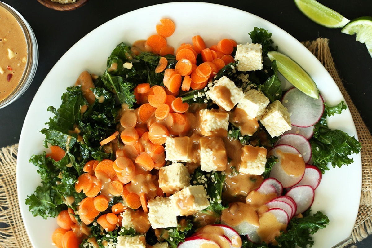 plate of crunchy thai kale salad with carrots tofu and radishes