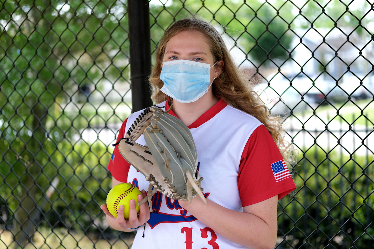 Teenage girl in her softball uniform posing with a healthcare mask to protect her from the Coronavirus