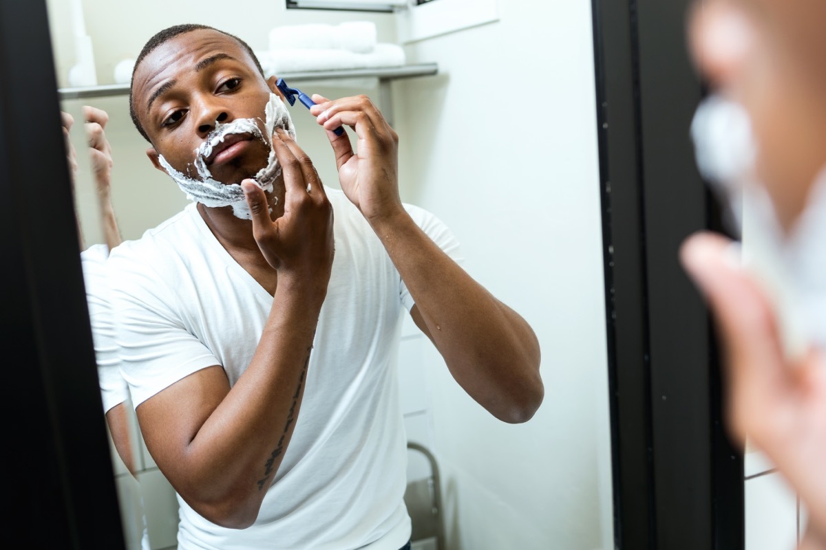 black man shaving in home bathroom