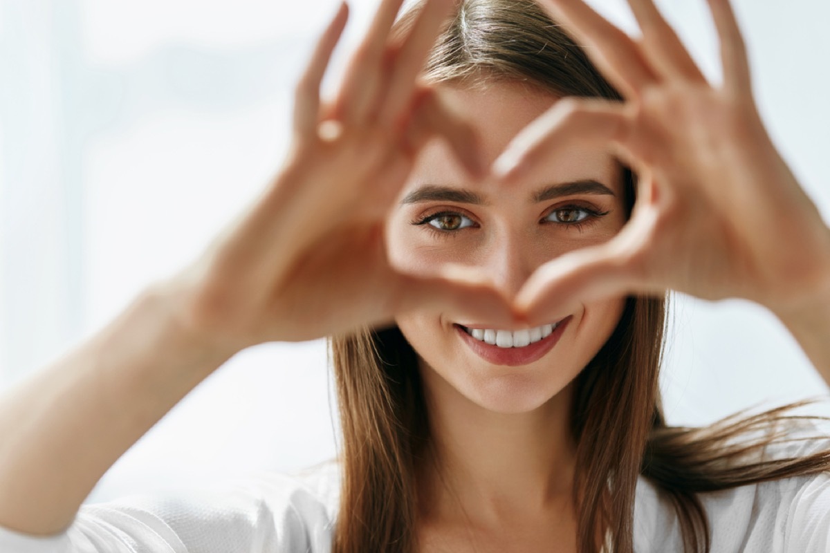 white woman making a heart with her hand around her eyes