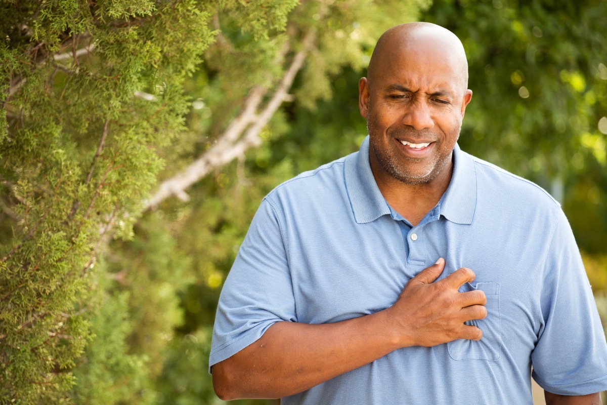 black man clutching his chest and grimacing outdoors
