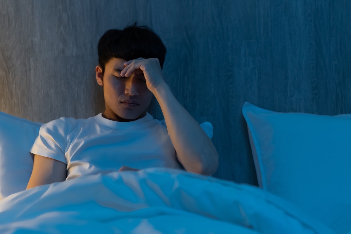 man is worrying about something on bed at night