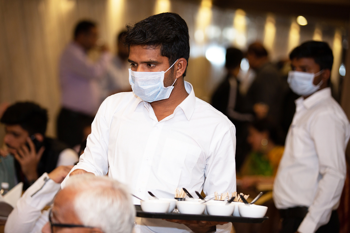 waiter wears mask at event, handling food