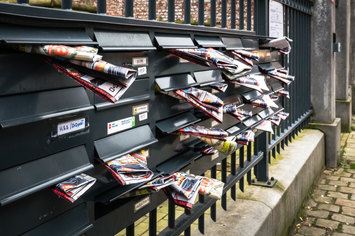 junk mail stuffed in the mailboxes of an apartment complex in brussels
