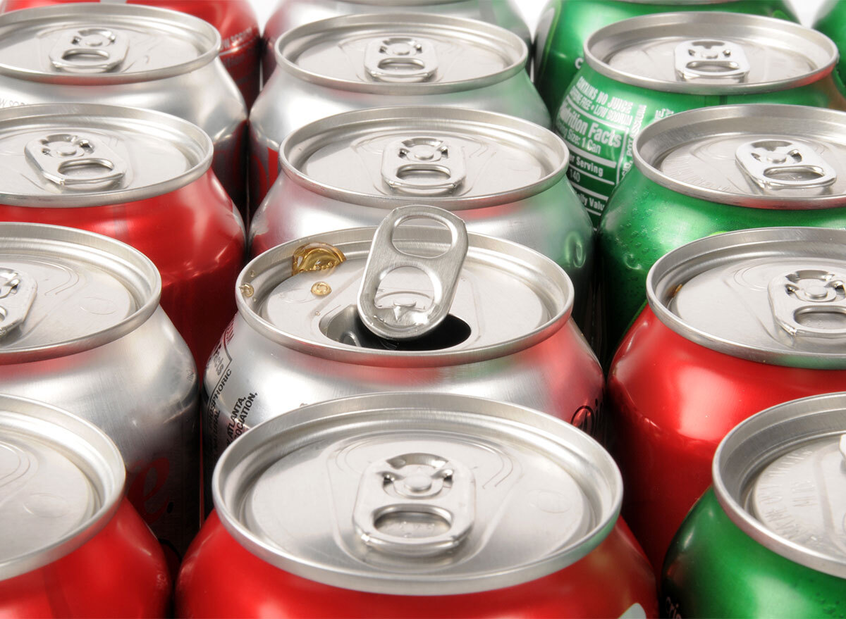 rows of soda cans with one can open