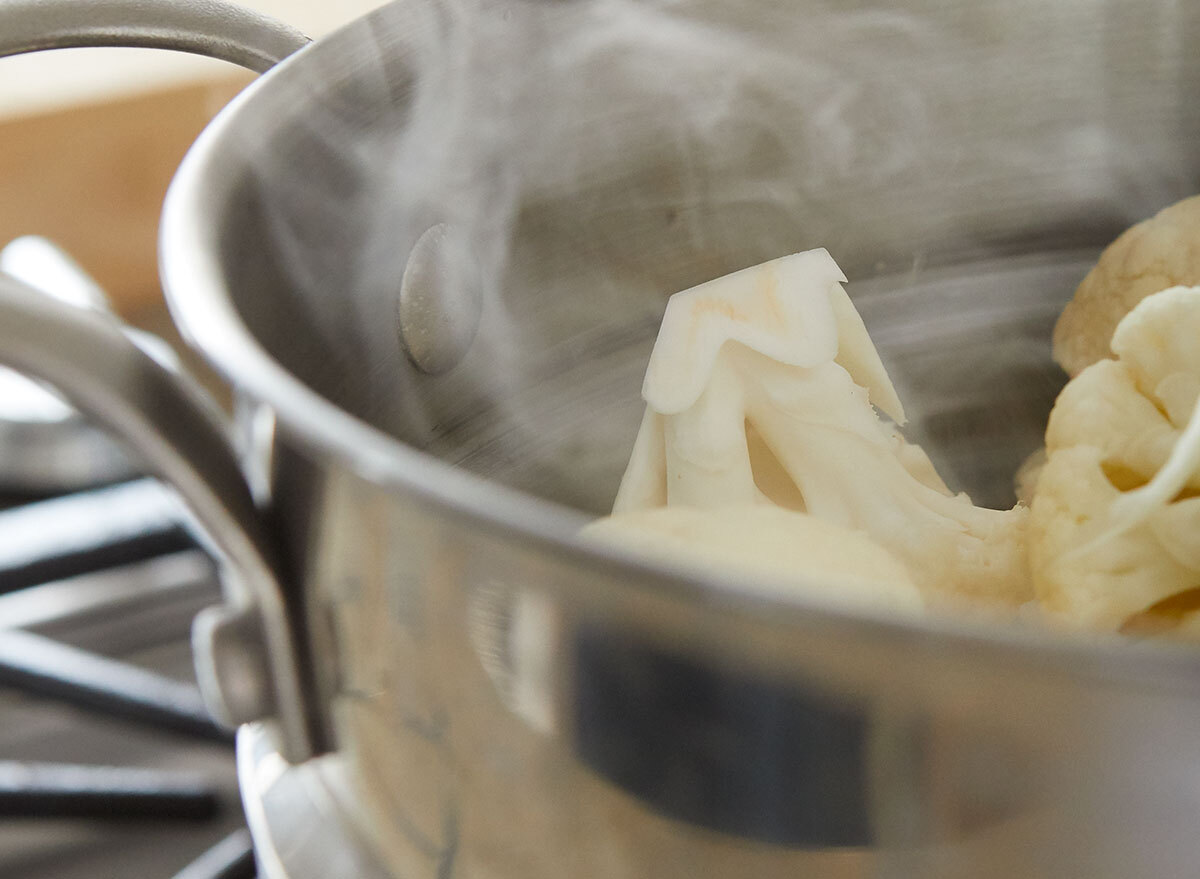 Steaming cauliflower in a steel basket on the stove
