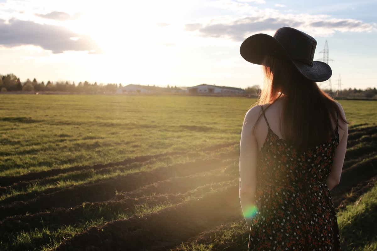 woman wearing a cowboy hat looking out over a field