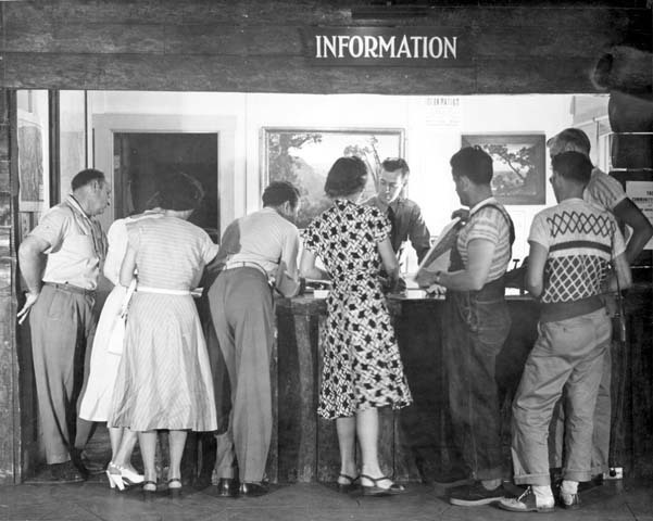 a line of people wait in front of an information booth