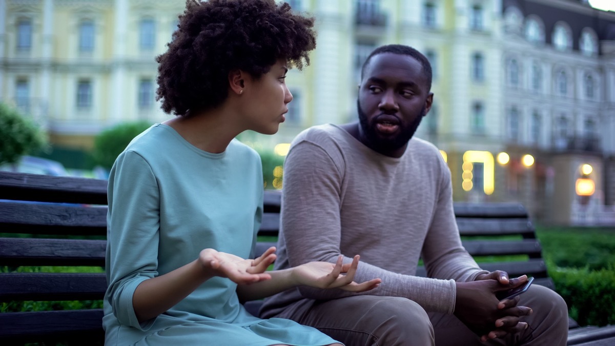young black couple talking outside on bench