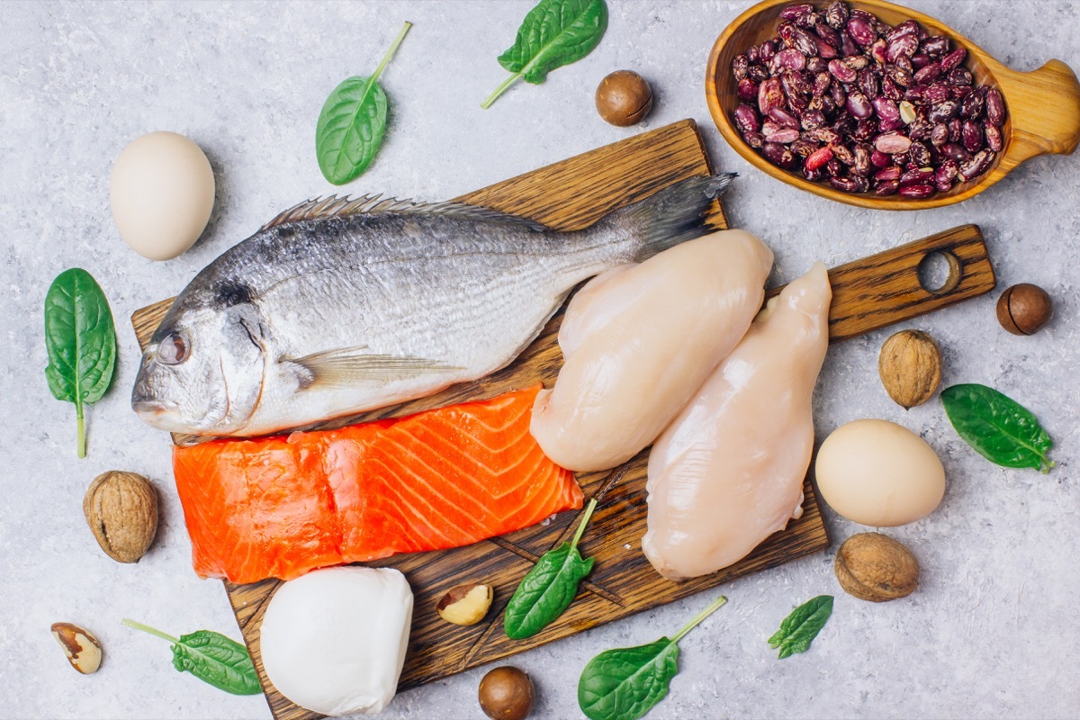 Assortment of healthy protein source and body building food. Salmon, chicken breast, eggs, mozzarella cheese, beans, nuts, spinach, flax and chia seeds. Top view. light background