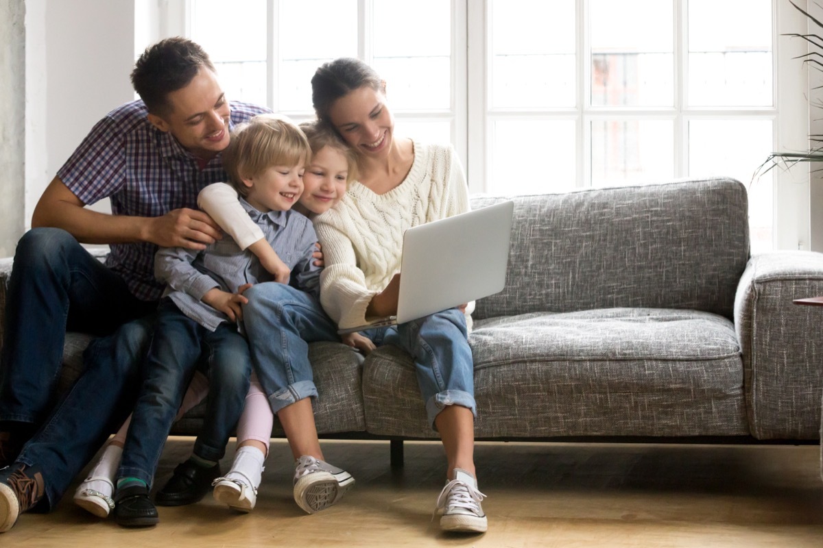 Family looking at the computer together smiling on the couch