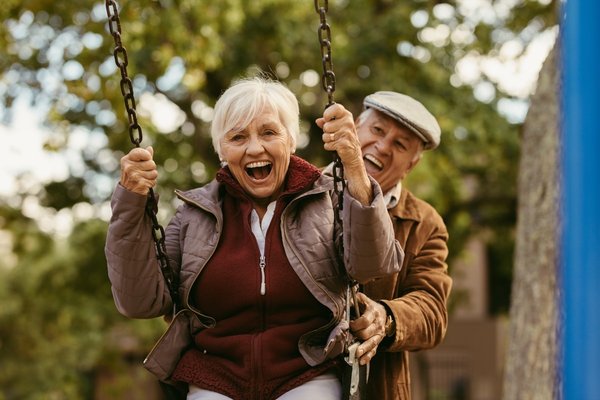 old man pushing his wife on a swing