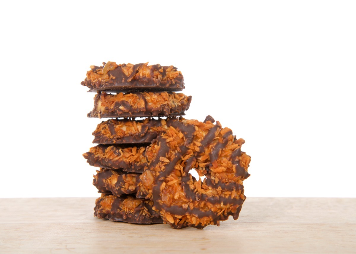 Stack of Girl Scout cookies, caramel delights, also known as Samoas, on a wood table with white background. Available annually during Girl Scout cookie sales.