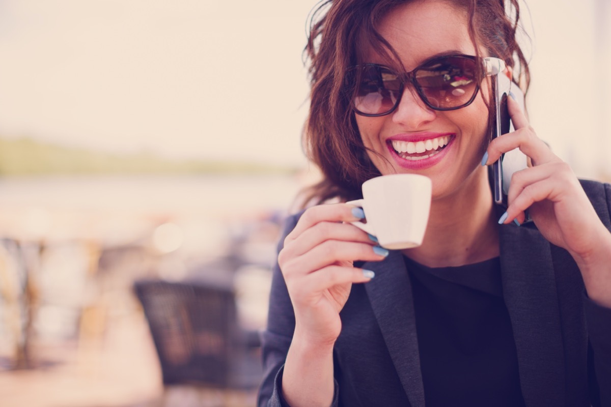 Woman drinking espresso and talking on the phone