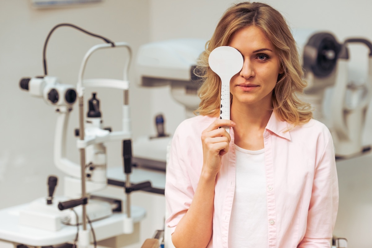 young blonde woman covering one eye at doctor's office