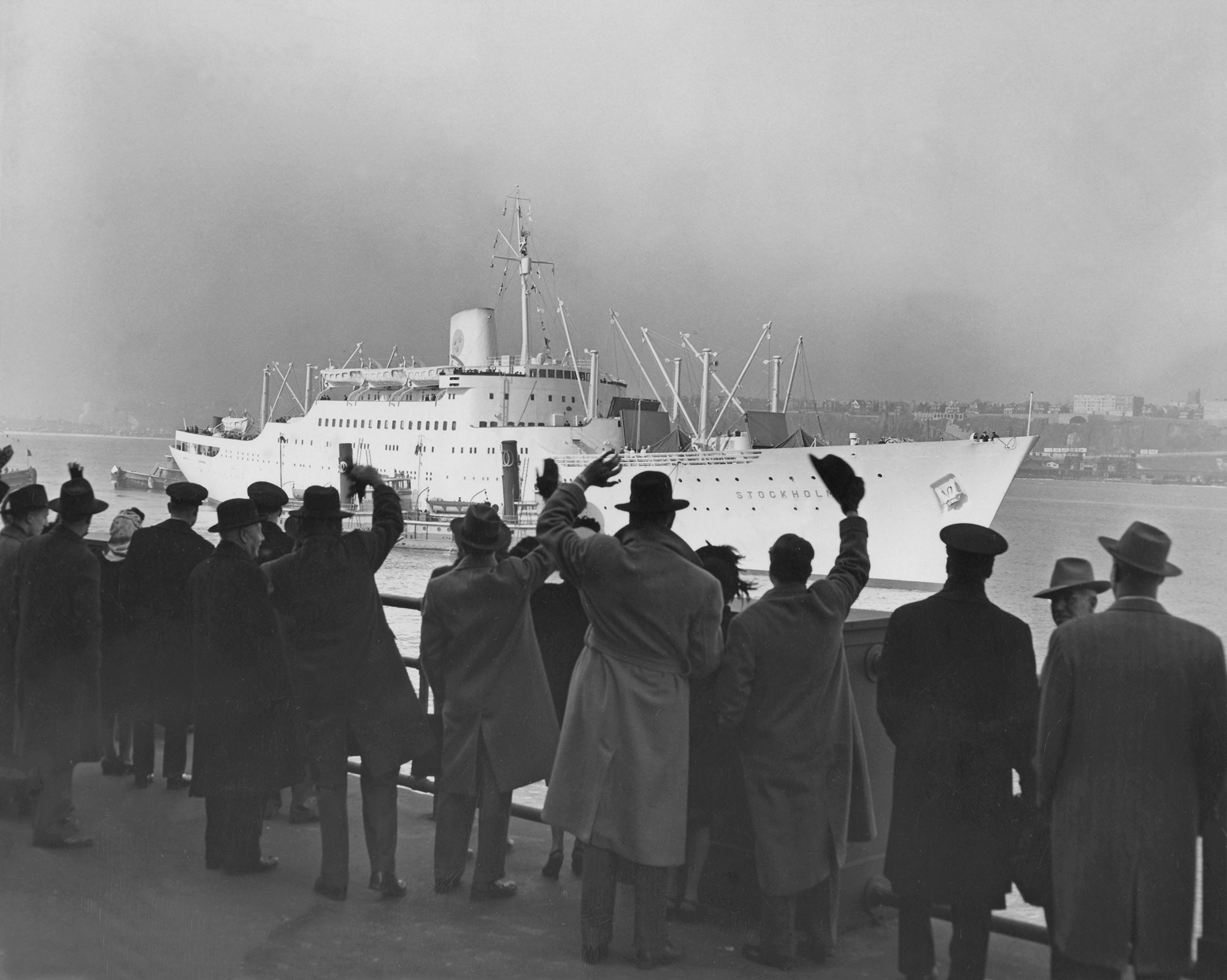 a group of people waves at a cruise ship