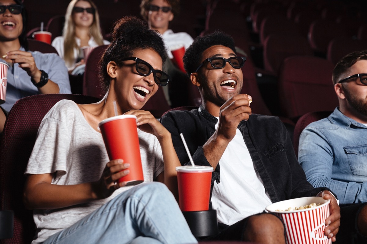 young black couple in movie theater laughing while watching a movie