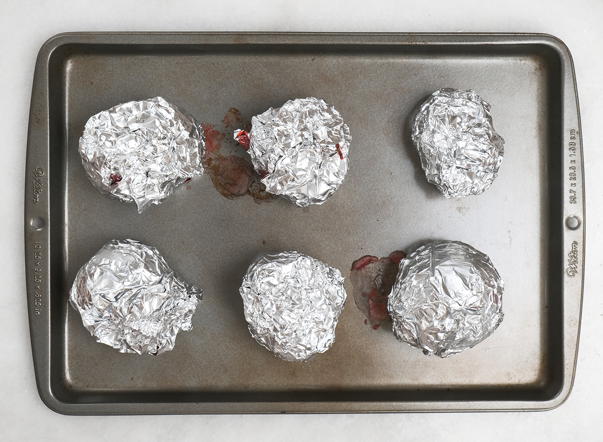 roasted beets wrapped in aluminum foil on a baking sheet