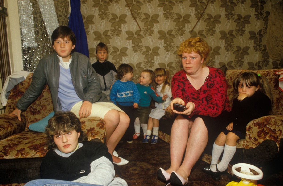 Single parent family. Mother and her seven children watching TV at home. Council estate Circa 1985