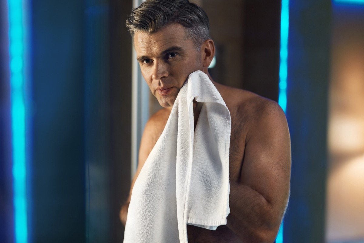 a man with gray hair holding a face towel