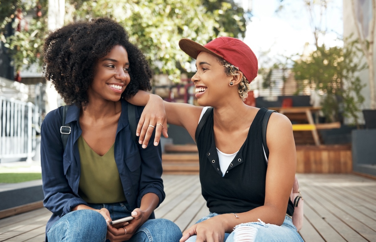 Smiling young women sitting outside and flirting