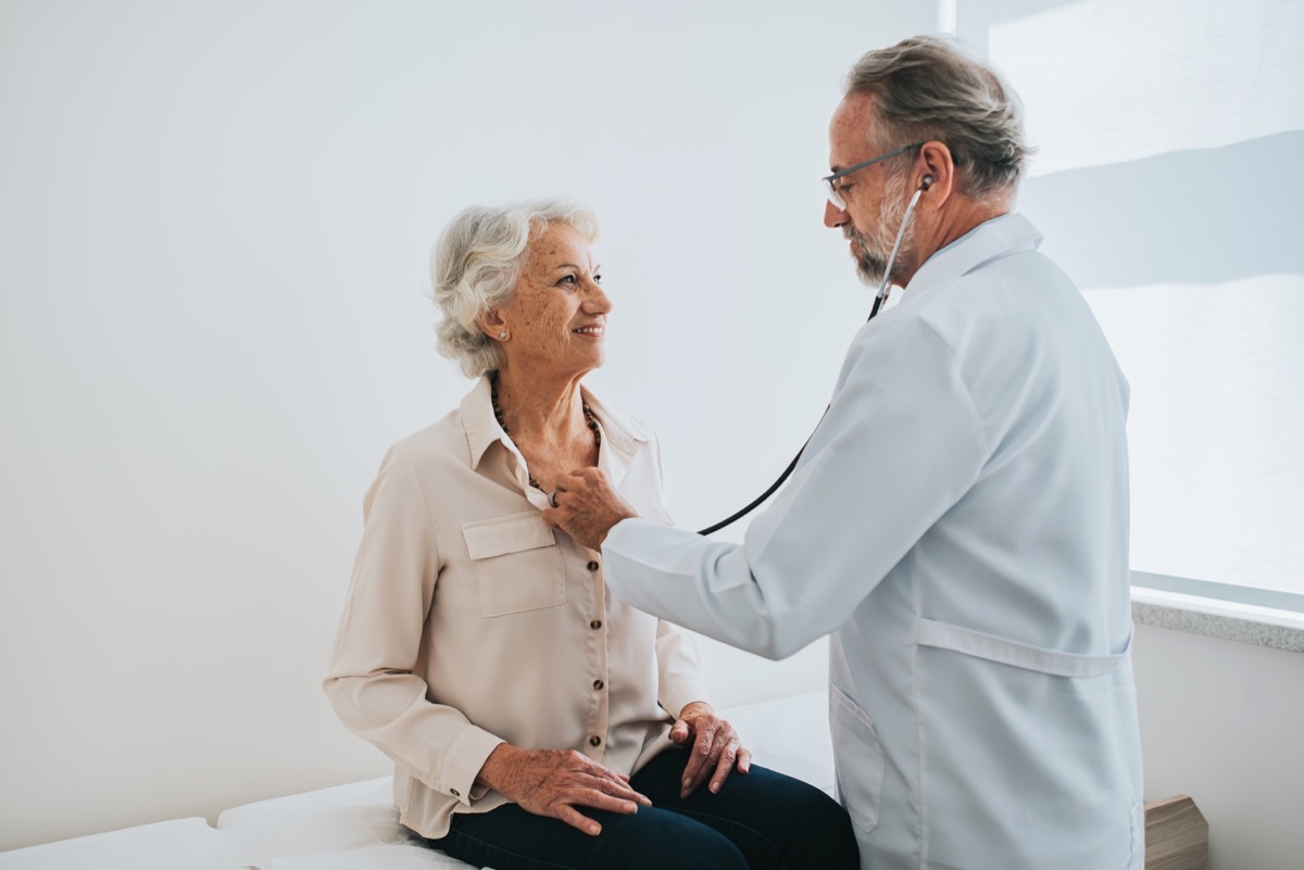 Doctor listening to senior woman patient heartbeat