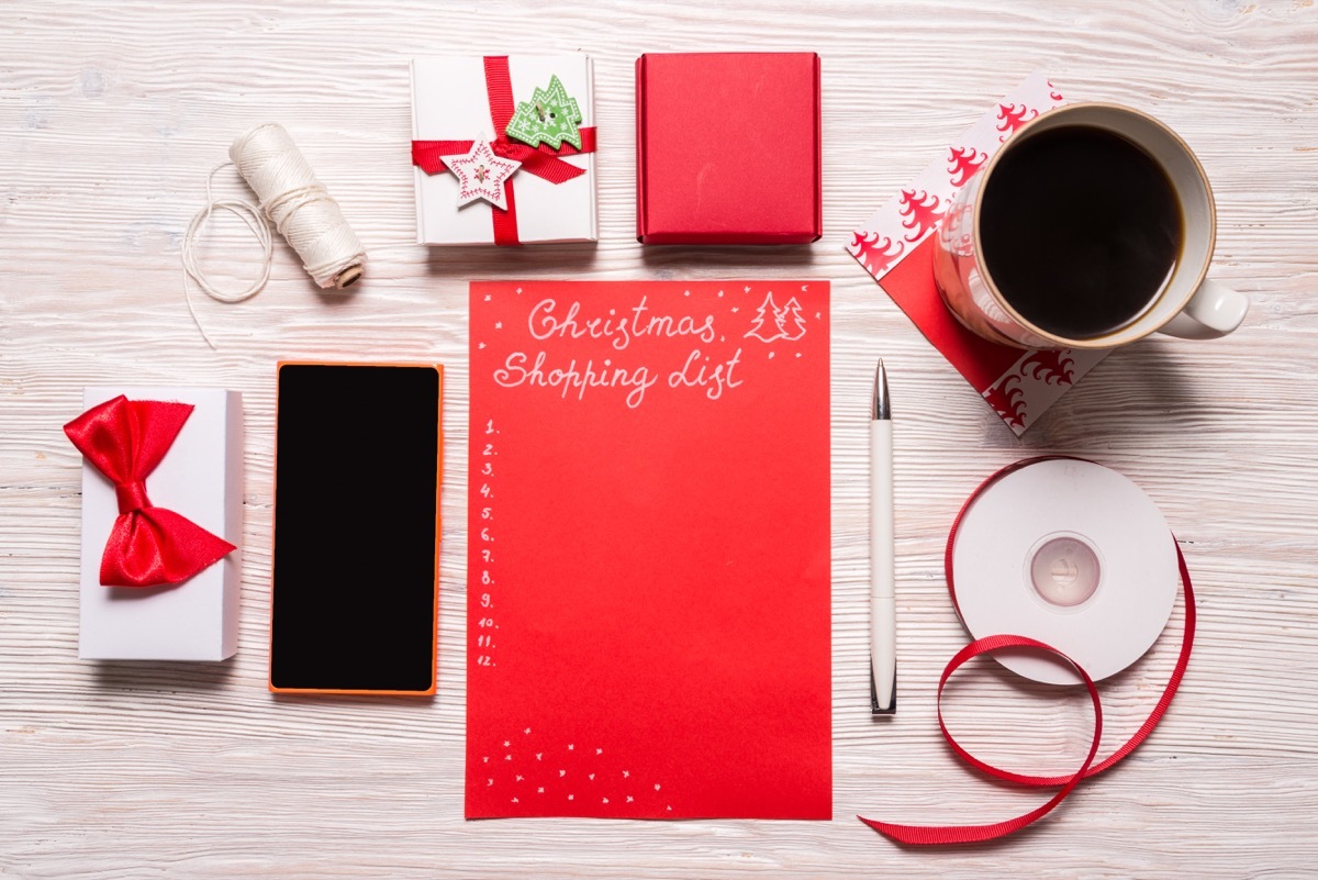 christmas shopping list with gift boxes and coffee cup on table