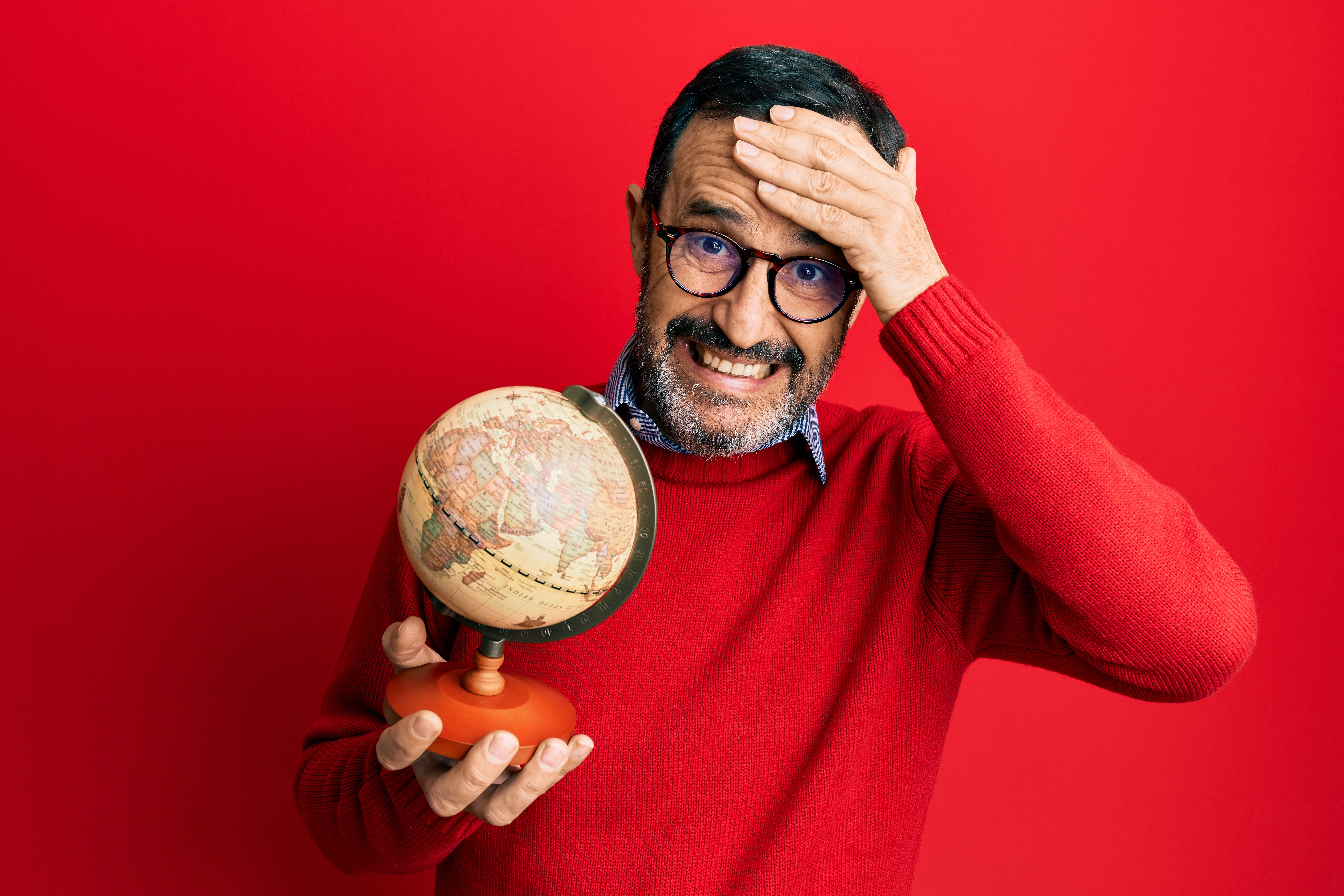 man holding a globe looking confused over geography quiz questions