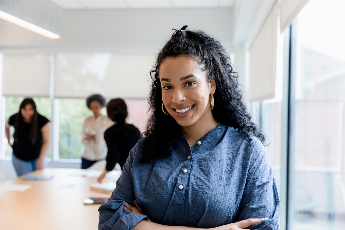 professional headshot of a woman with people working behind her