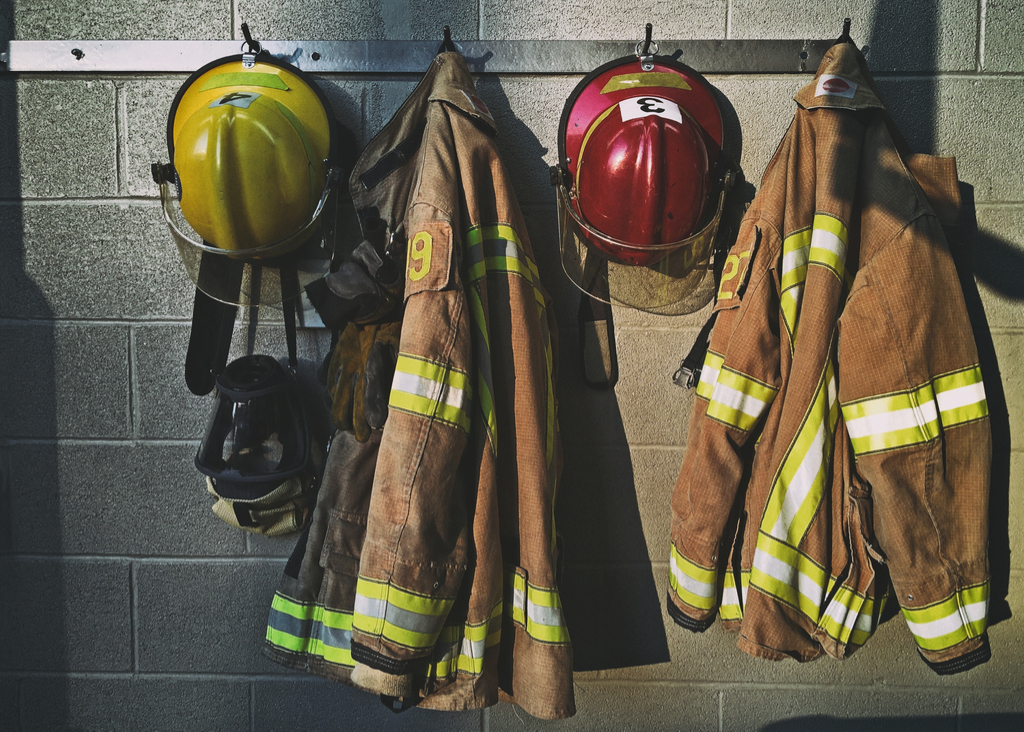 firefighters uniforms hanging on hooks at fire house