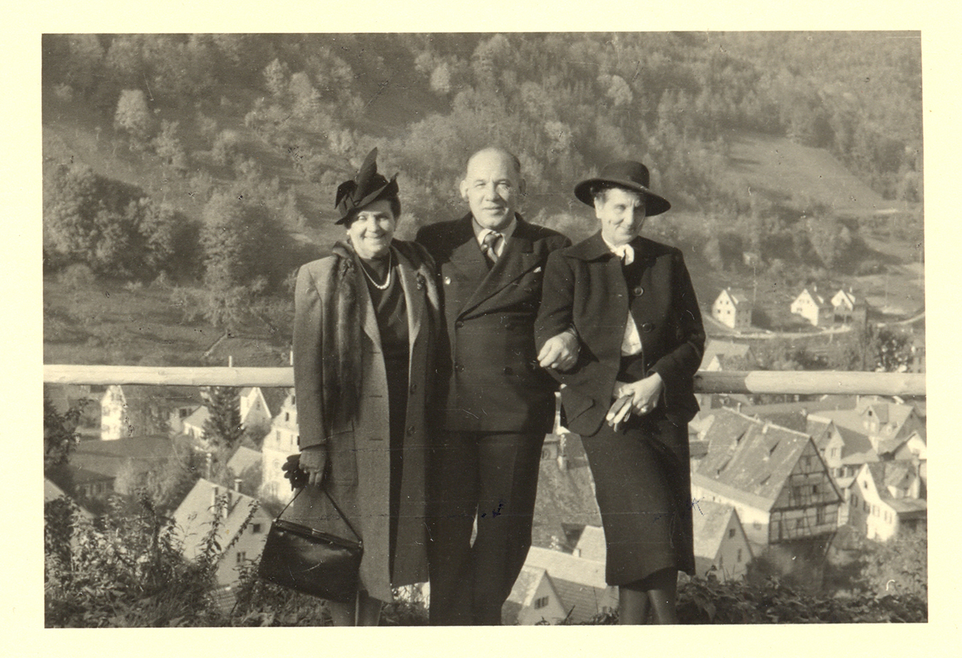 a man and two women pose in front of a european village