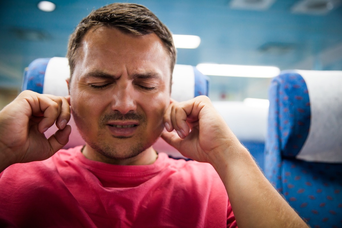 Traveling man on an airplane, experiencing air ache