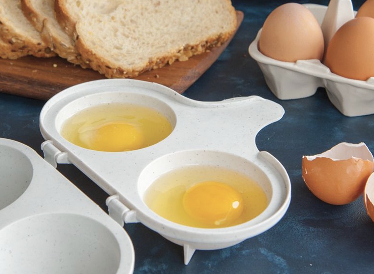 two eggs in a white container next to sliced bread