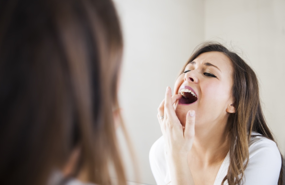 Woman looking her self in mirror, she have toothache