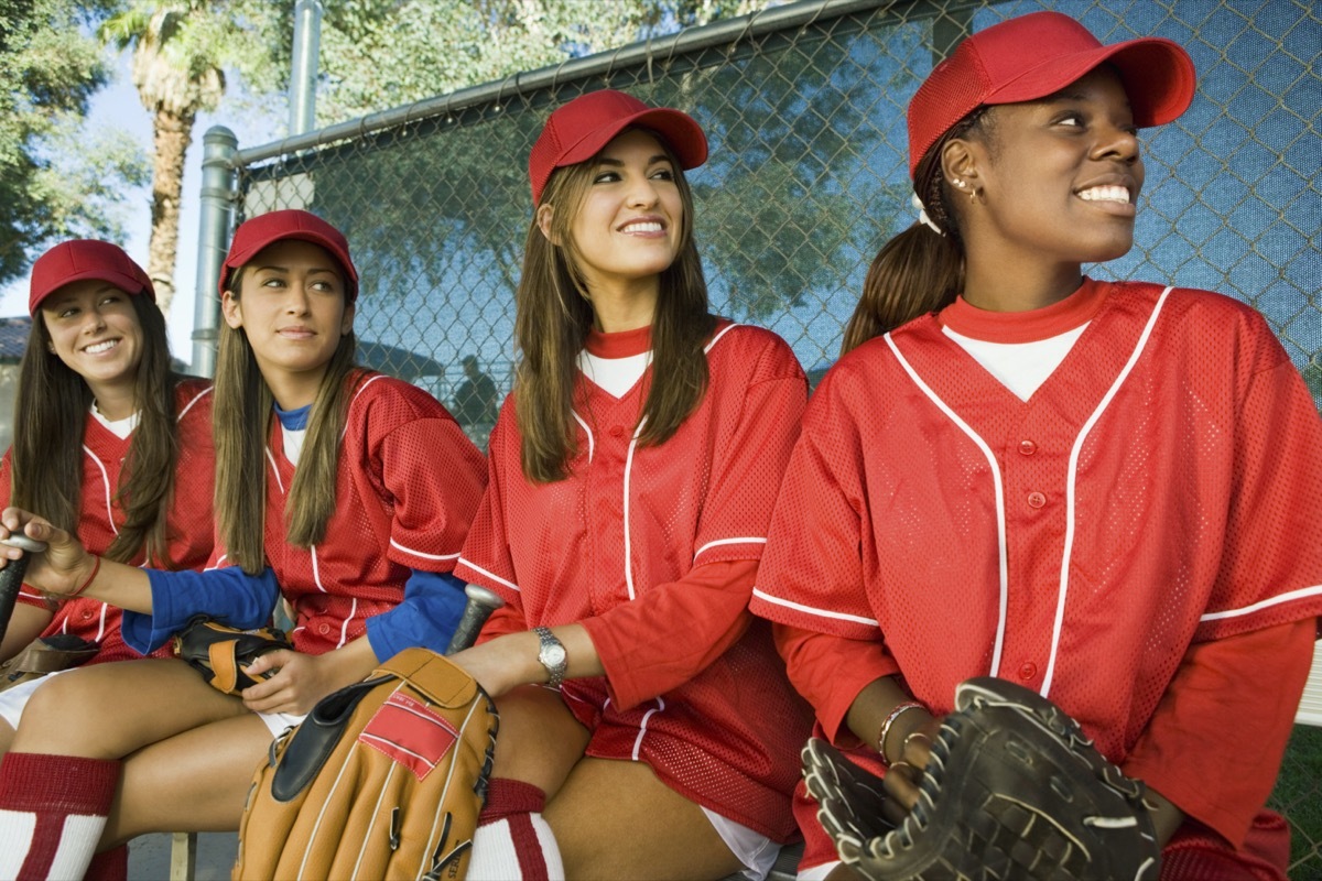 Young women on softball team sitting in dugout